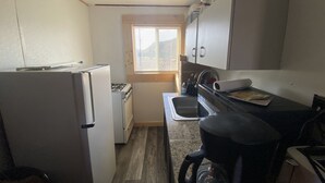Une cuisine compacte équipée d’un réfrigérateur, d’une cuisinière, d’un évier et d’une machine à café.