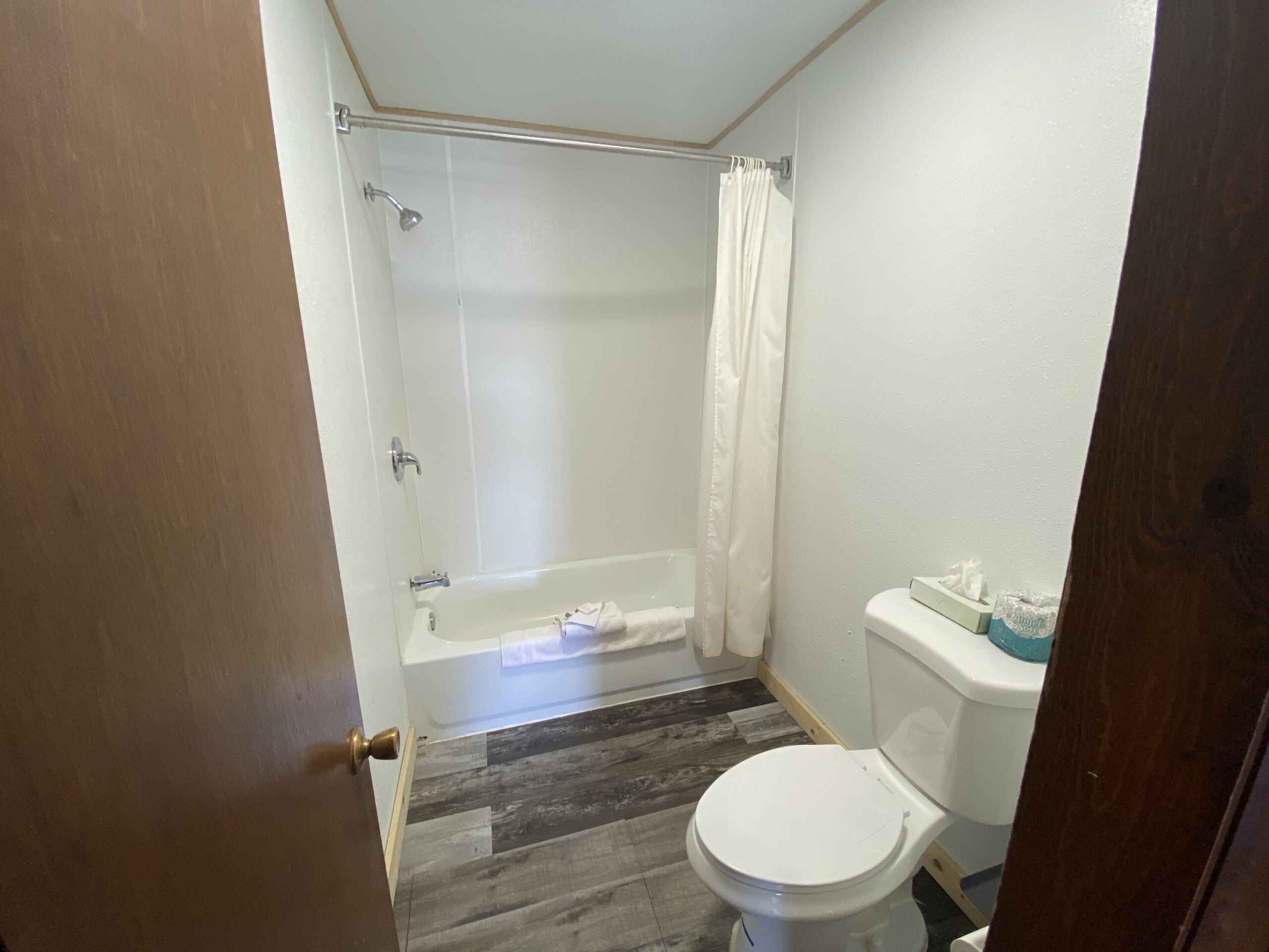 Ein Badezimmer mit Dusche, Toilette und Holzboden.