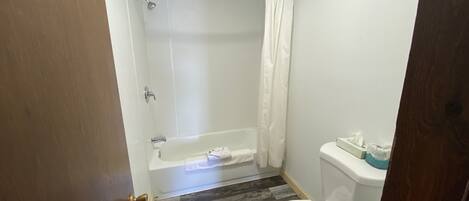 Ein Badezimmer mit Dusche, Toilette und Holzboden.