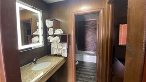Une salle de bain avec un lavabo doté d’un plan de travail en granit, un miroir avec un éclairage intégré et un porte-serviettes avec des serviettes pliées.