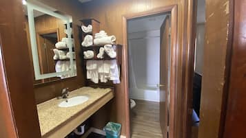Ein Badezimmer mit Waschbecken, Spiegel, Handtuchhalter und einer Tür zu einer Duschkabine.