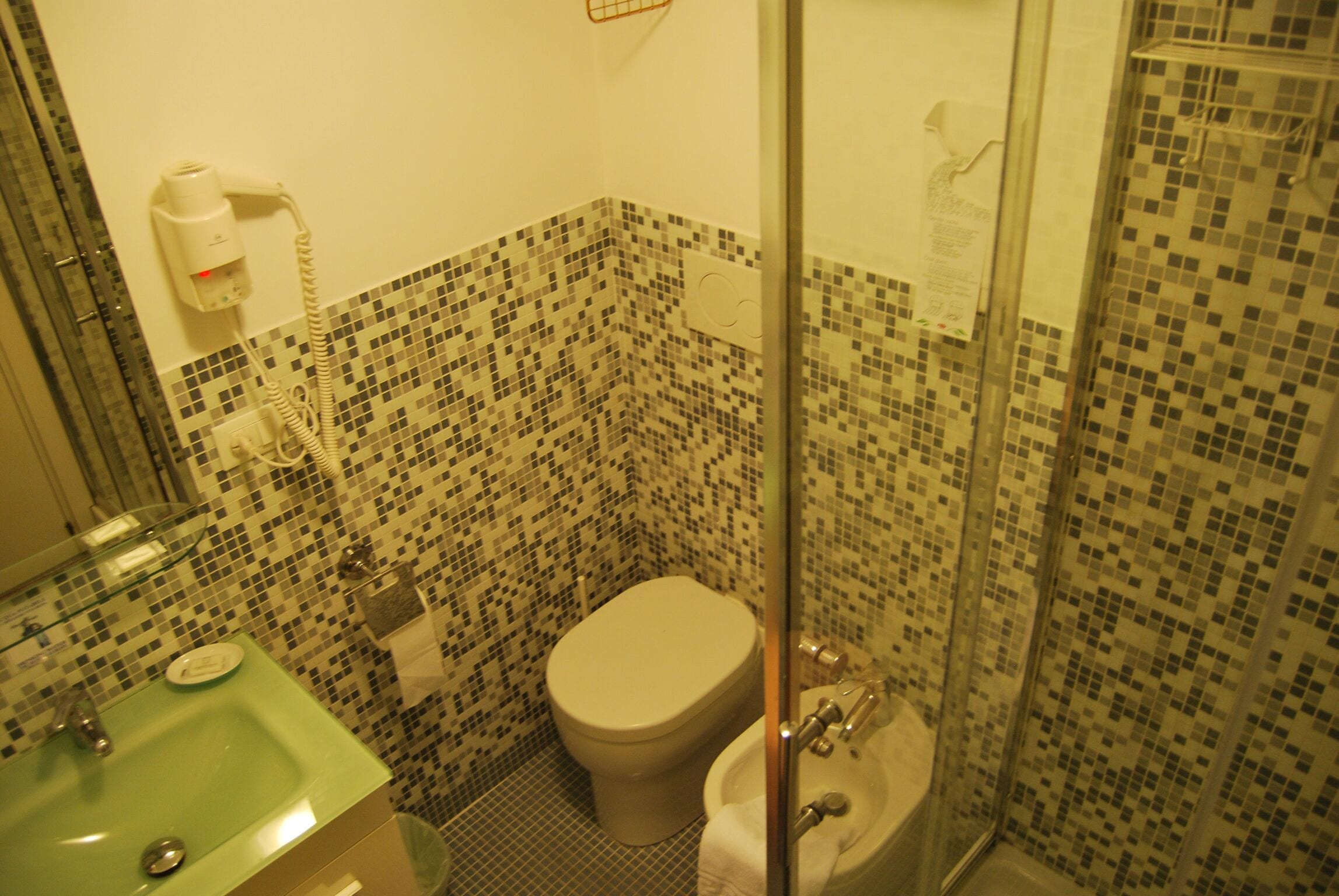 Un baño con inodoro, lavamanos y zona de ducha.