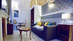 A living room with a sofa, a coffee table, a lamp, and a fireplace. - Navona Residenza de Charme (Rome)