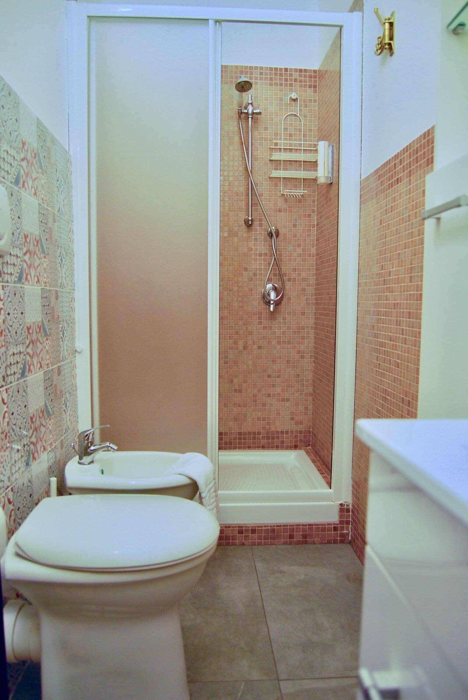 Ein Badezimmer mit Toilette, einer Dusche mit Glastür und einer gefliesten Wand.
