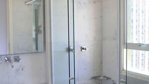Un bagno moderno con cabina doccia in vetro, lavabo in marmo e un ampio specchio.