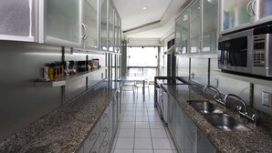 A modern kitchen with granite countertops, stainless steel appliances, and a view to the outdoors. - Rio034 - Penthouse Arpoador (Rio de Janeiro)