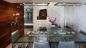 A modern conference room with a glass table, leather chairs, and a wooden accent wall. - Rio034 - Penthouse Arpoador (Rio de Janeiro)
