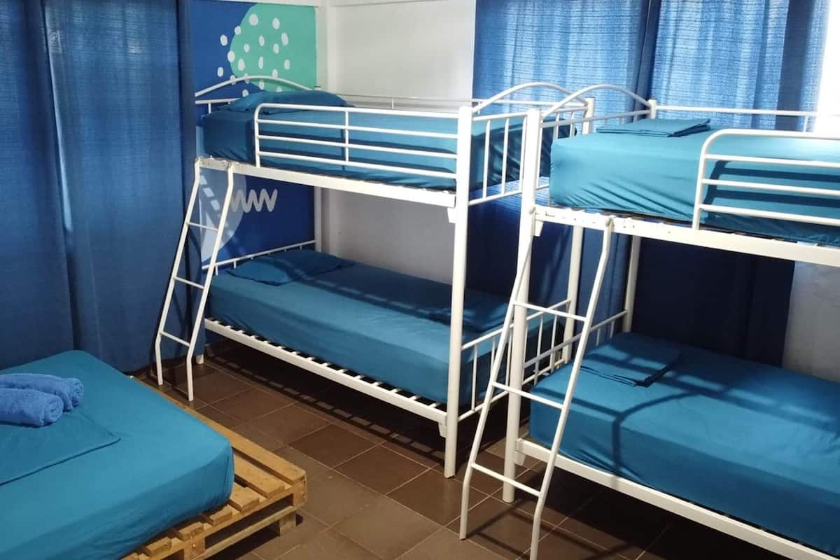 Habitación con literas, ropa de cama y cortinas azules.