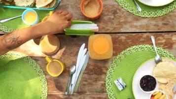 Una mesa de comedor con varios individuales verdes, platos con comida y diversos utensilios.