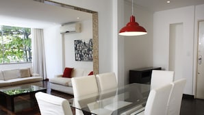 A modern living room with a glass-top dining table, white sofas, and a red pendant light. - Rio045 - Apartment Ipanema (Rio de Janeiro)