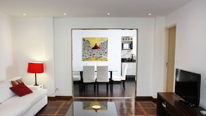 A modern living room with a white sofa, a red lamp, a coffee table, and a TV on a wooden stand. - Rio045 - Apartment Ipanema (Rio de Janeiro)