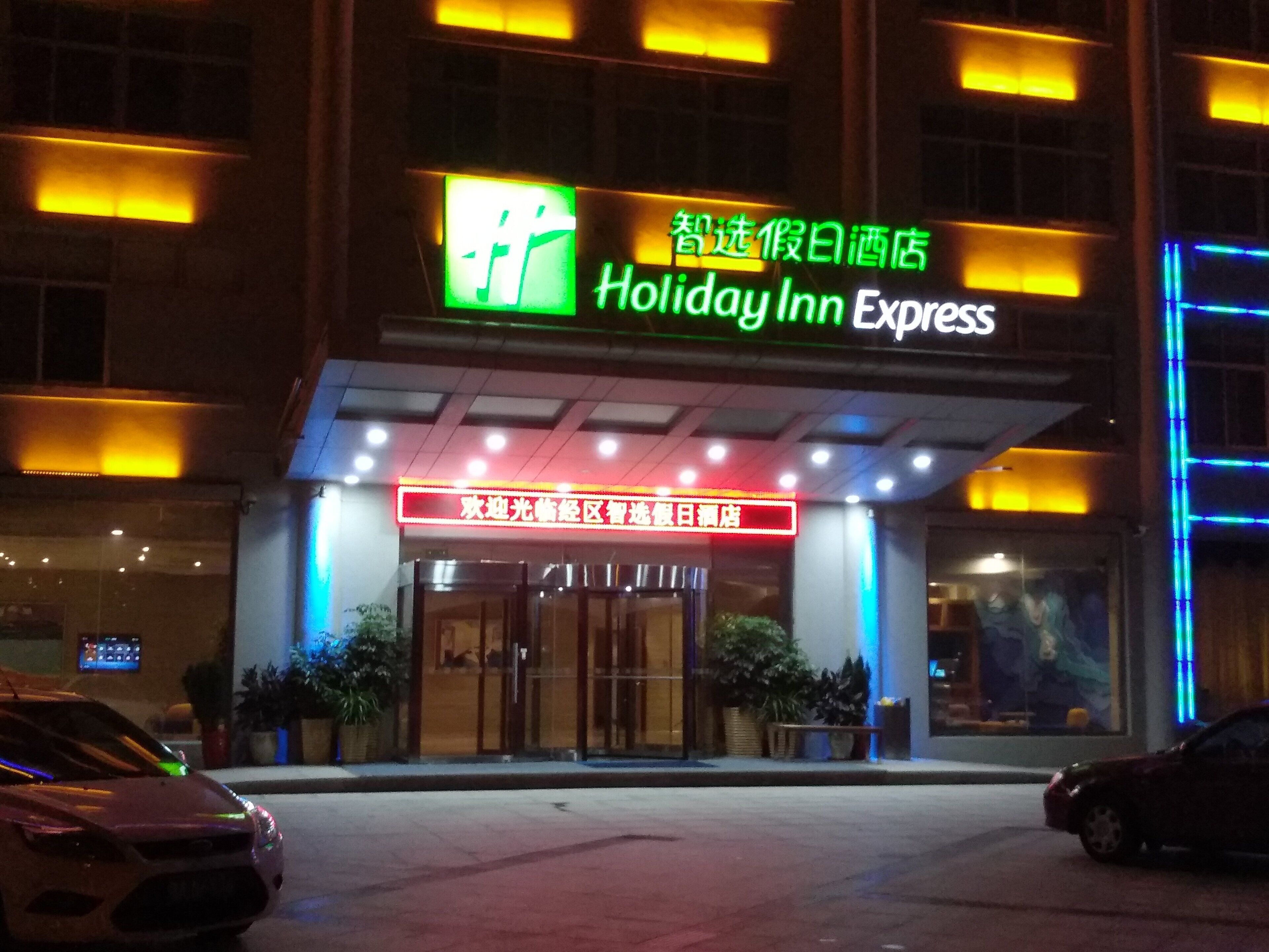 Entrada de un hotel Holiday Inn Express con señalización iluminada y puerta de cristal.