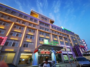 A hotel with multiple floors, a covered entrance, and illuminated signage. - Holiday Inn Express-Weihai Economic Zone by IHG (Weihai)
