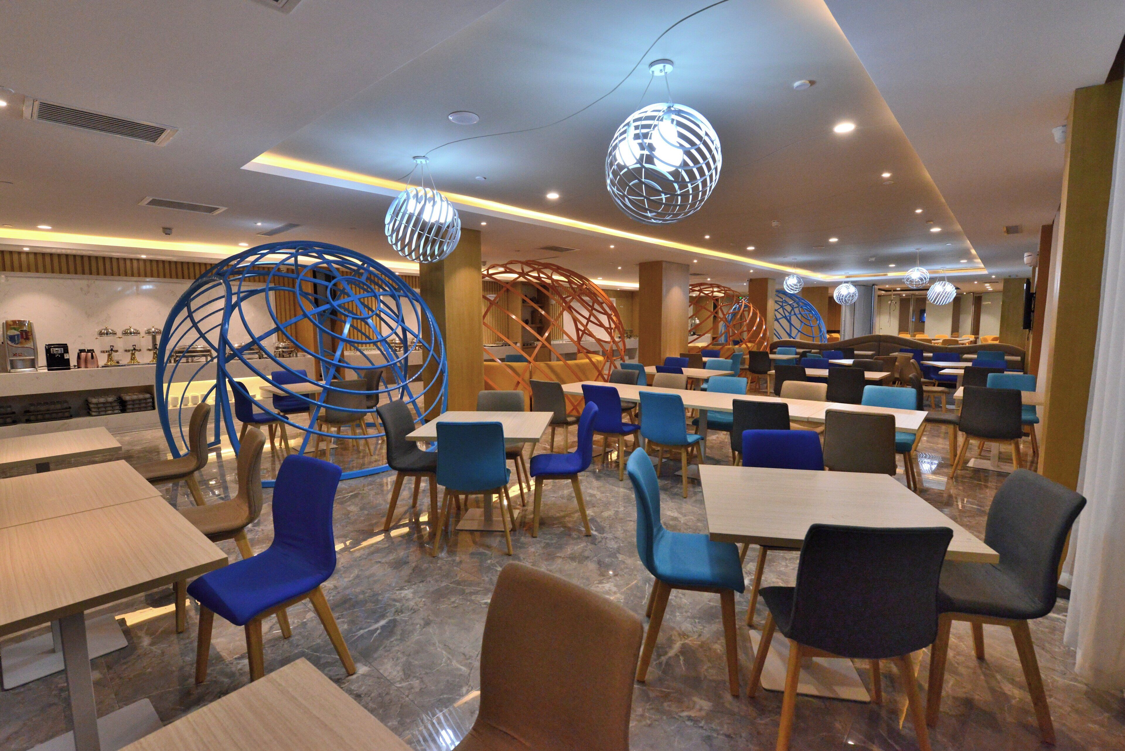 A modern dining area with multiple tables and chairs, decorative spherical light fixtures, and a clean, contemporary design.