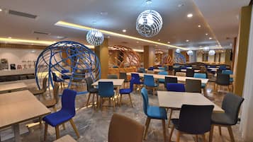 A modern dining area with multiple tables and chairs, decorative spherical light fixtures, and a clean, contemporary design.