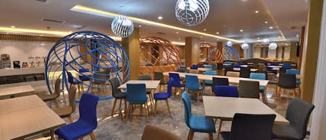 A modern dining area with multiple tables and chairs, decorative spherical light fixtures, and a clean, contemporary design.