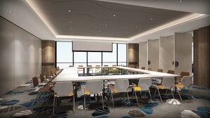 A conference room with a long table, chairs, and a large screen.