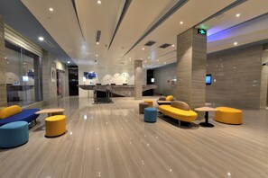 A modern lobby with seating areas, a reception desk, and a large screen. - Holiday Inn Express-Weihai Economic Zone by IHG (Weihai)