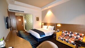 Une chambre d’hôtel avec un lit, un canapé, un bureau et une télévision.