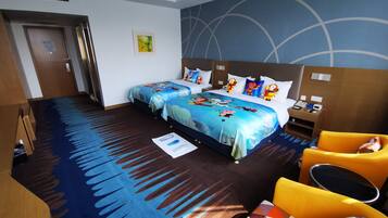 Two double beds with matching bedding and cartoon character pillows, a wooden headboard with phone, and a desk near the window.