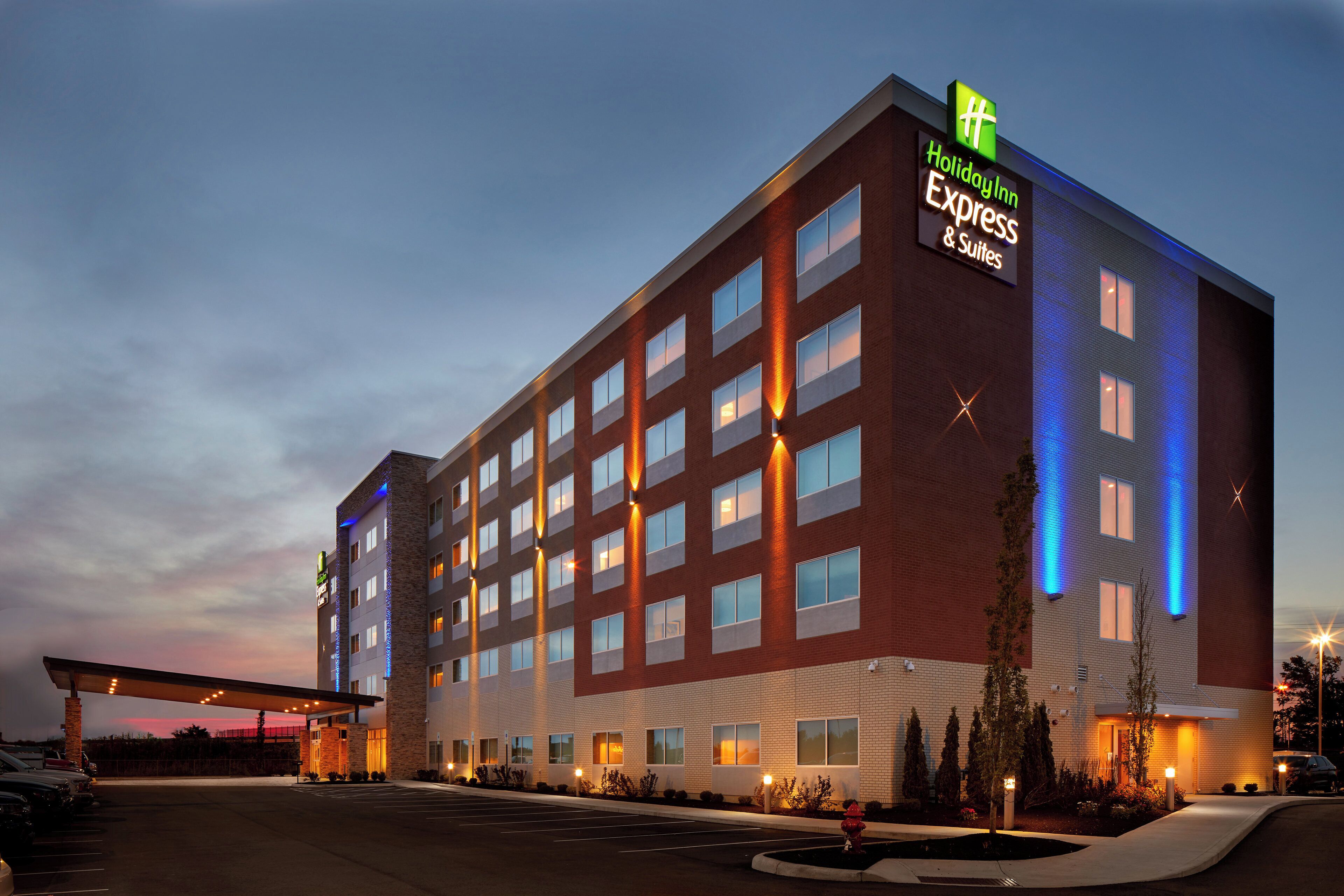 Un hotel Holiday Inn Express & Suites con fachada de ladrillo, varias ventanas y un estacionamiento.