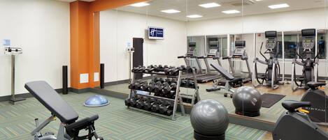 A gym with various exercise equipment including treadmills, stationary bikes, and free weights.