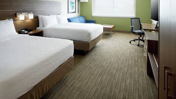 A hotel room with two beds, a desk, a chair, a TV, and a lamp.