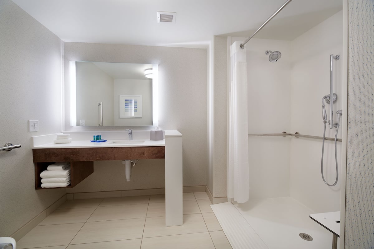 A modern bathroom with a white vanity, a large mirror, a shower with a glass door, and a toilet.