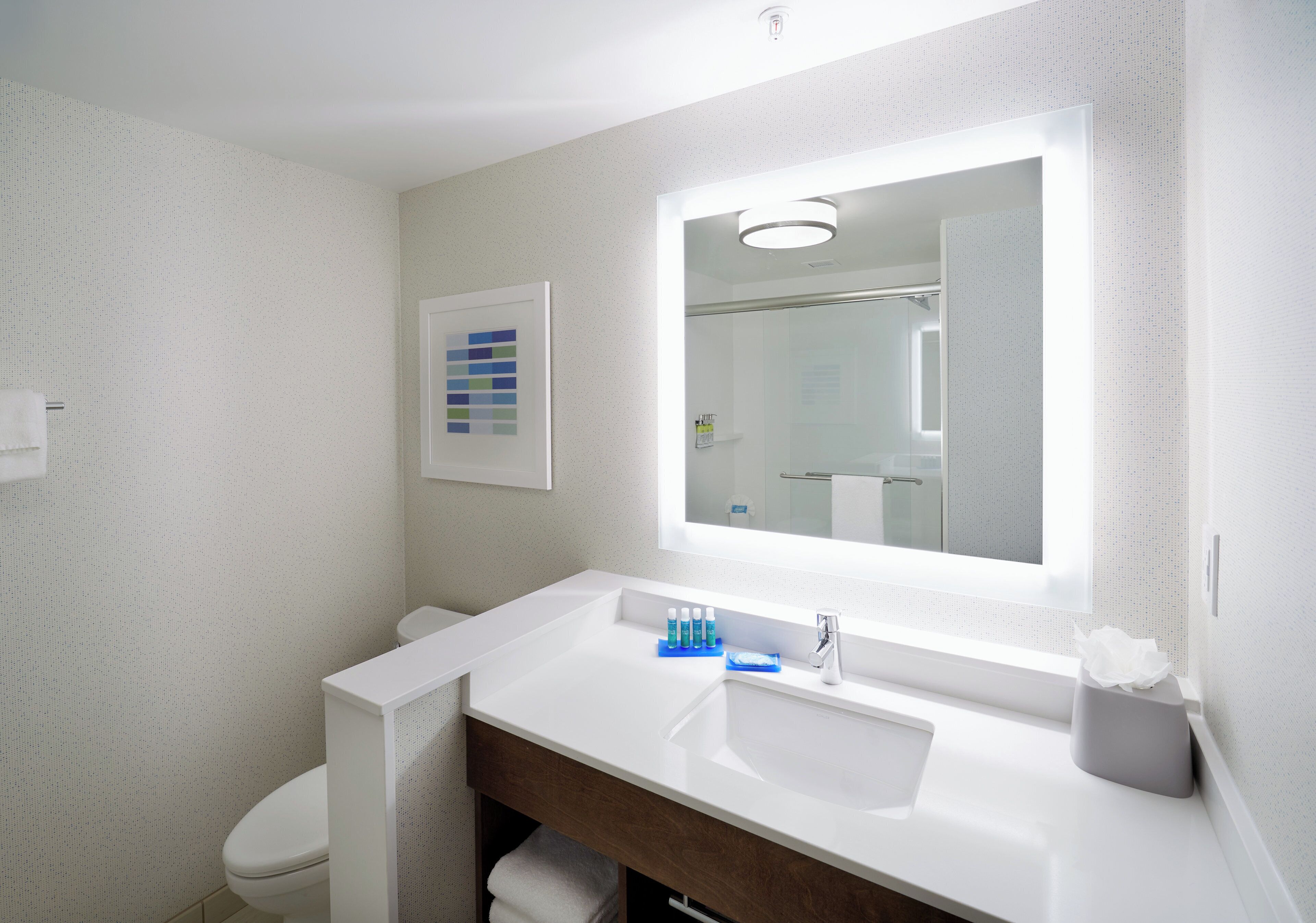 Un baño con lavamanos blanco, espejo y retrete.