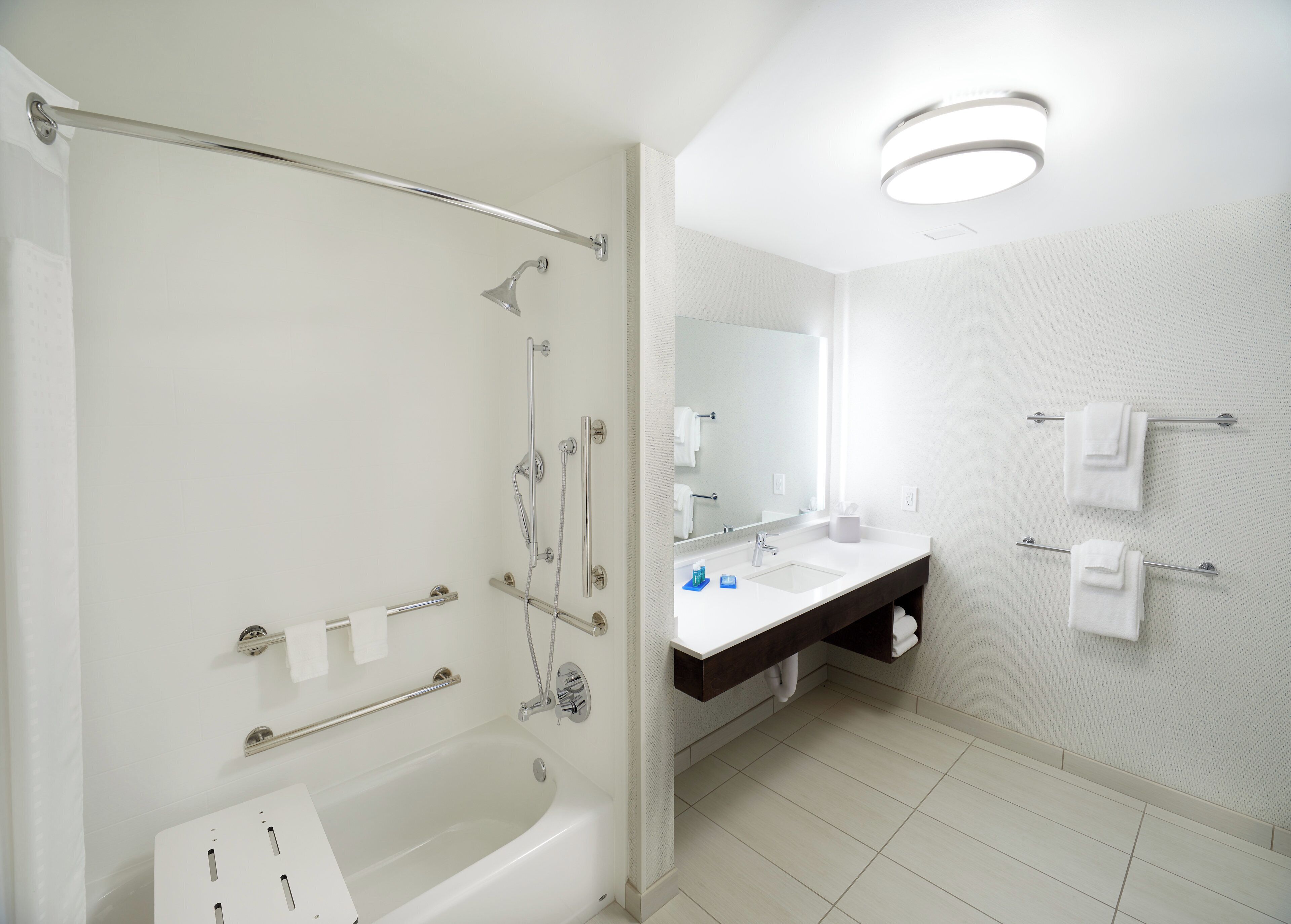 A modern bathroom with a bathtub, shower, vanity, and towel racks.