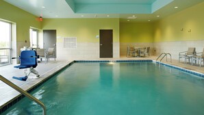 A swimming pool with a blue border, a chair, and a table with chairs around it. - Holiday Inn Express & Suites-Cincinnati North - Liberty Way by IHG (West Chester)