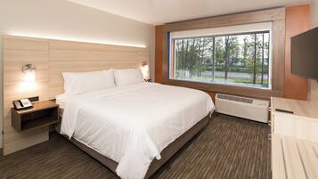 Habitación de hotel con cama, lámparas de noche, teléfono, ventana con vistas y televisor de pantalla plana.
