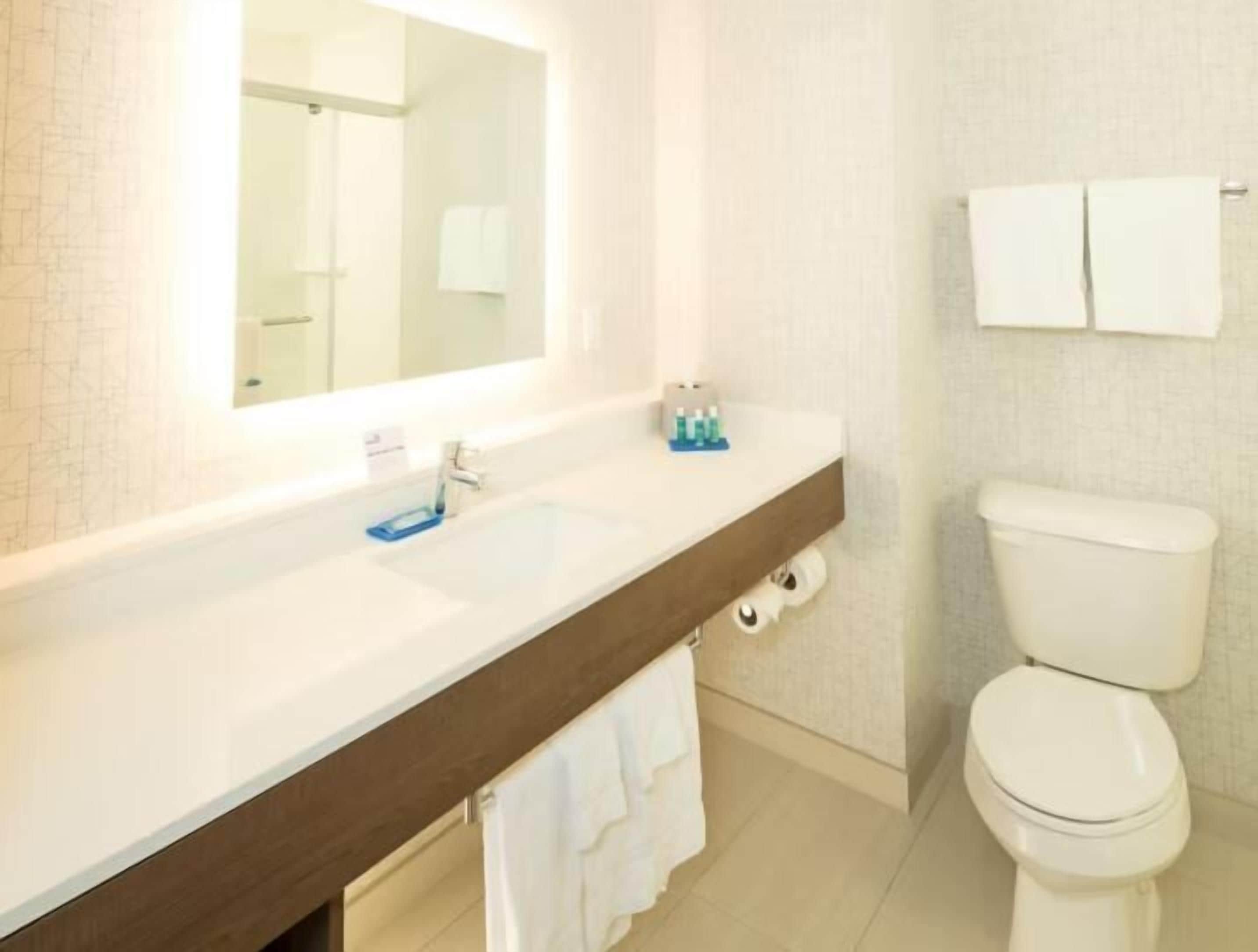 A bathroom with a white sink, mirror, and toilet.
