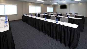 Une salle de conférence équipée de plusieurs tables, de plaques nominatives et de bouteilles d’eau.