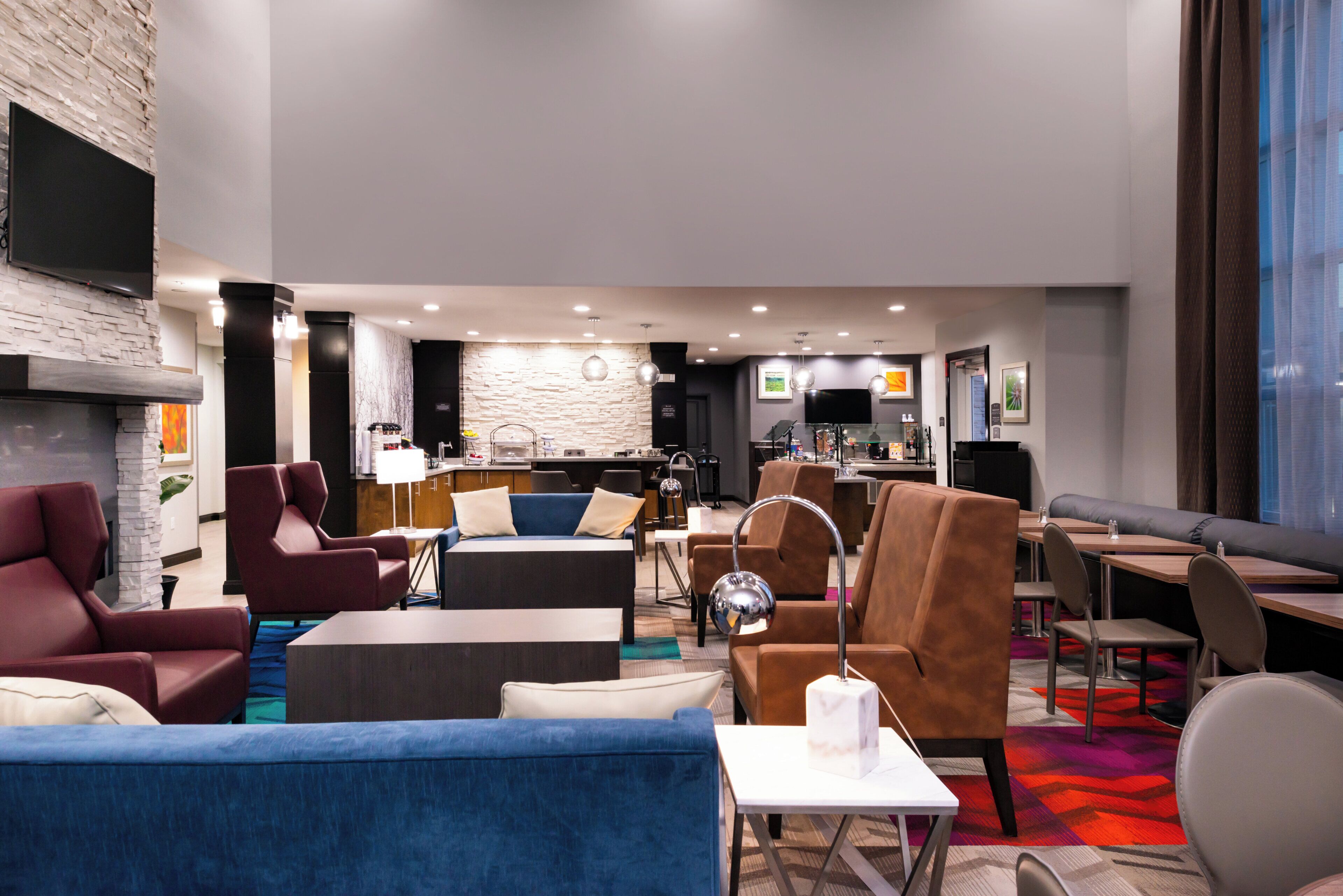 A hotel lobby with seating areas, a bar, and a television mounted on the wall.