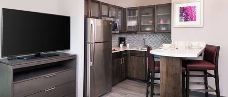 Una cocina moderna con televisor de pantalla plana, electrodomésticos de acero inoxidable y un comedor con mesa redonda y sillas.