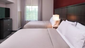 A hotel room with two beds, a television, a nightstand with a lamp, and a window with curtains.