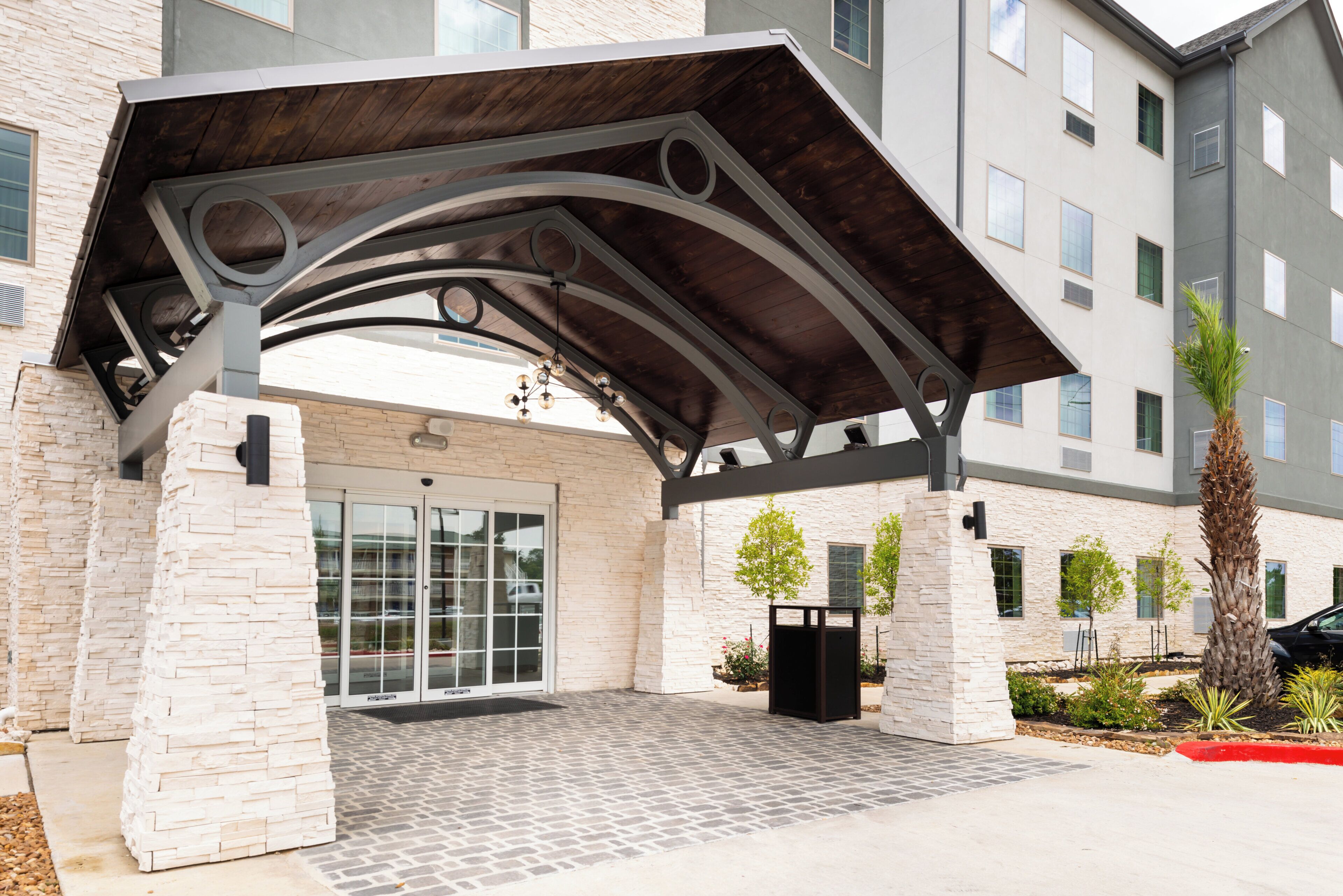 A building entrance with a covered patio area, stone facade, and a modern design.