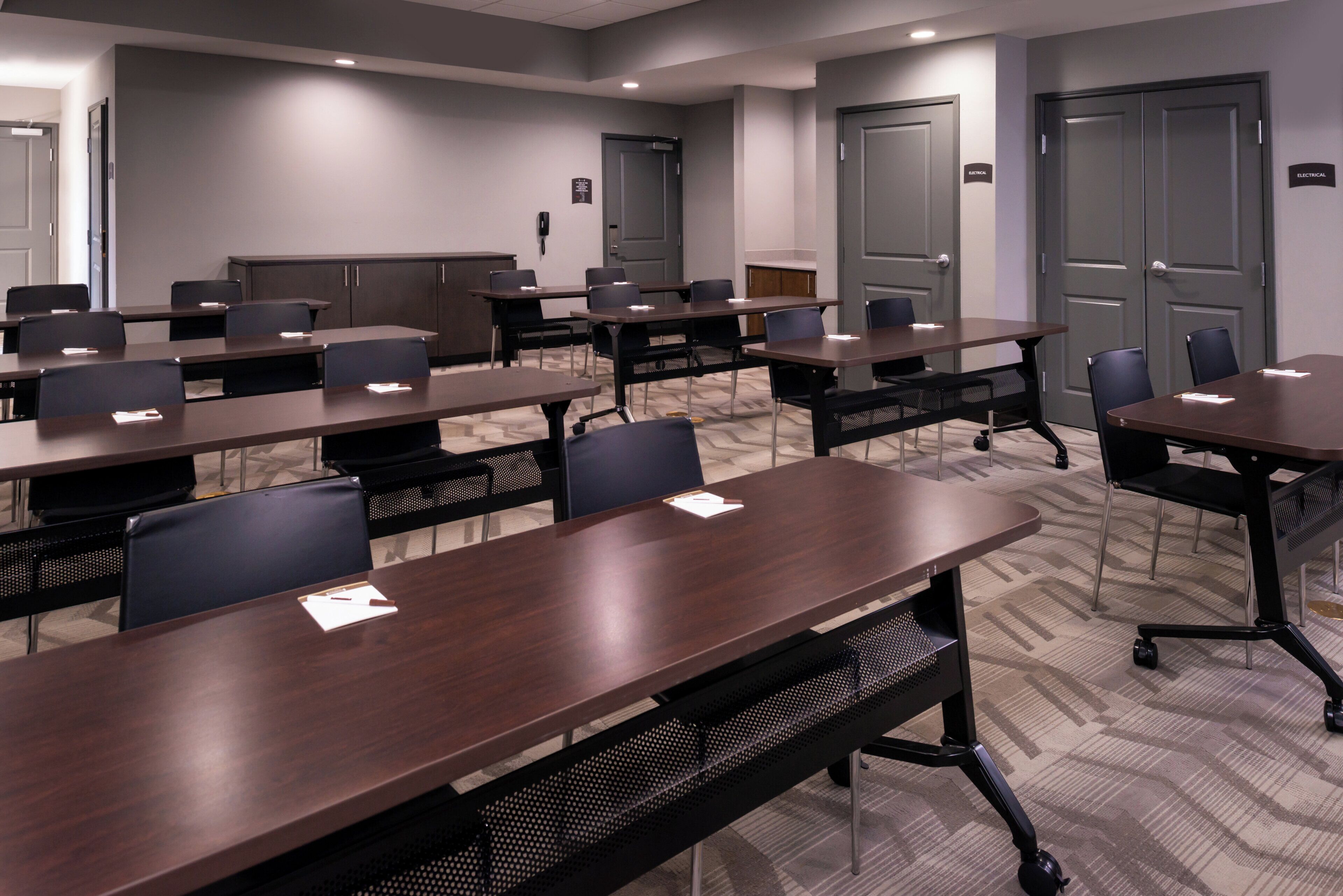 A conference room with multiple tables and chairs, equipped with nameplates and pens.