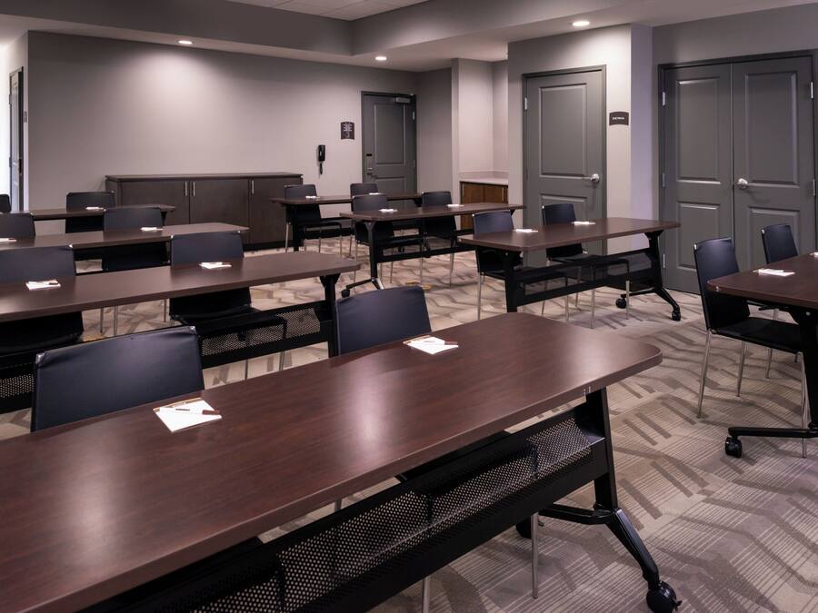 A conference room with multiple tables and chairs, equipped with nameplates and pens.