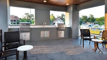An outdoor patio with a grill, seating, and a view of the surrounding area.