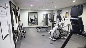 A fitness room with treadmills, weight machines, and a mirror.