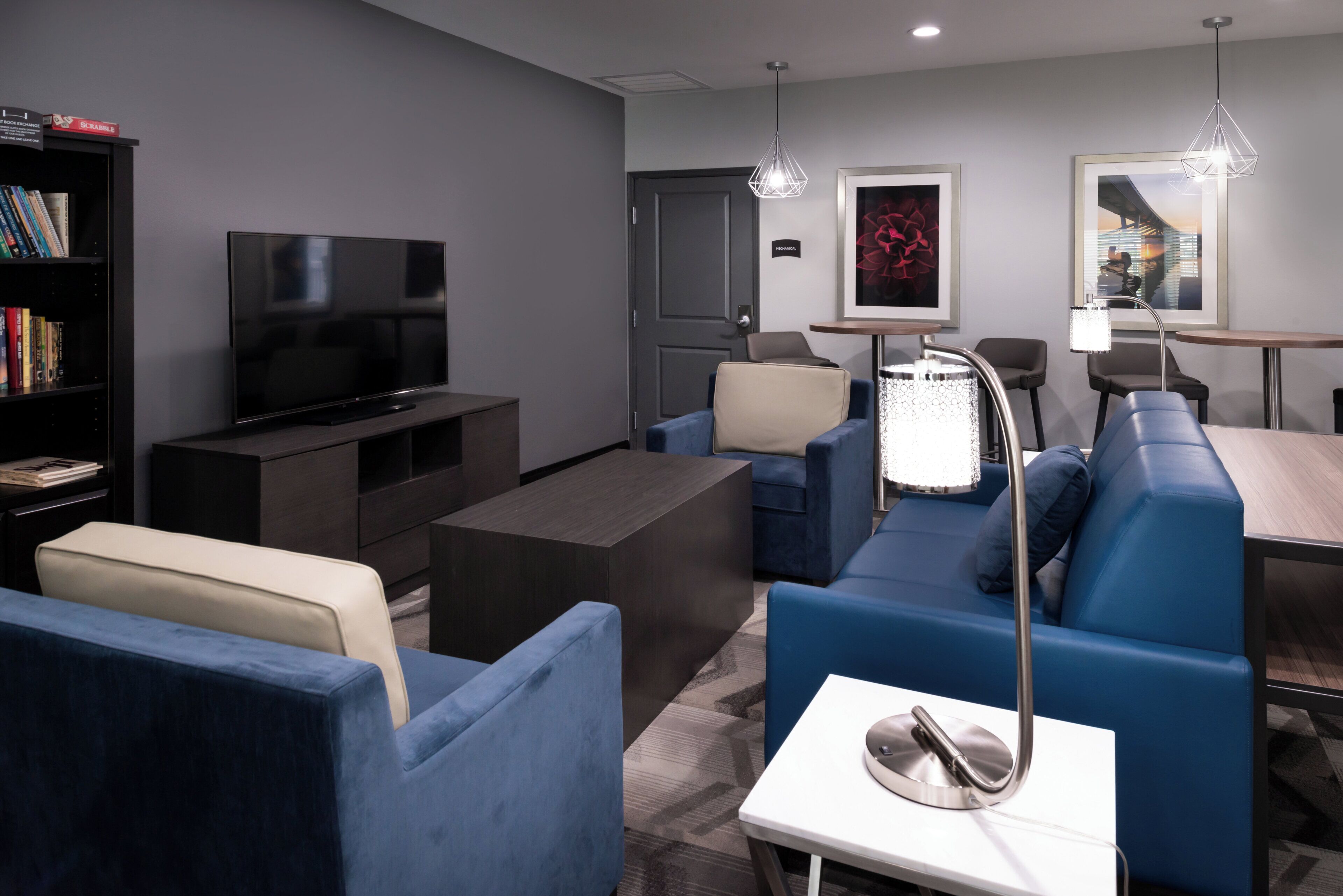 A modern living room with a flat-screen TV, a sofa set, a coffee table, and a bookshelf.