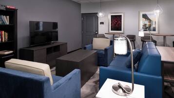 A modern living room with a flat-screen TV, a sofa set, a coffee table, and a bookshelf.