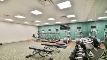 A gym with treadmills, elliptical machines, and free weights.