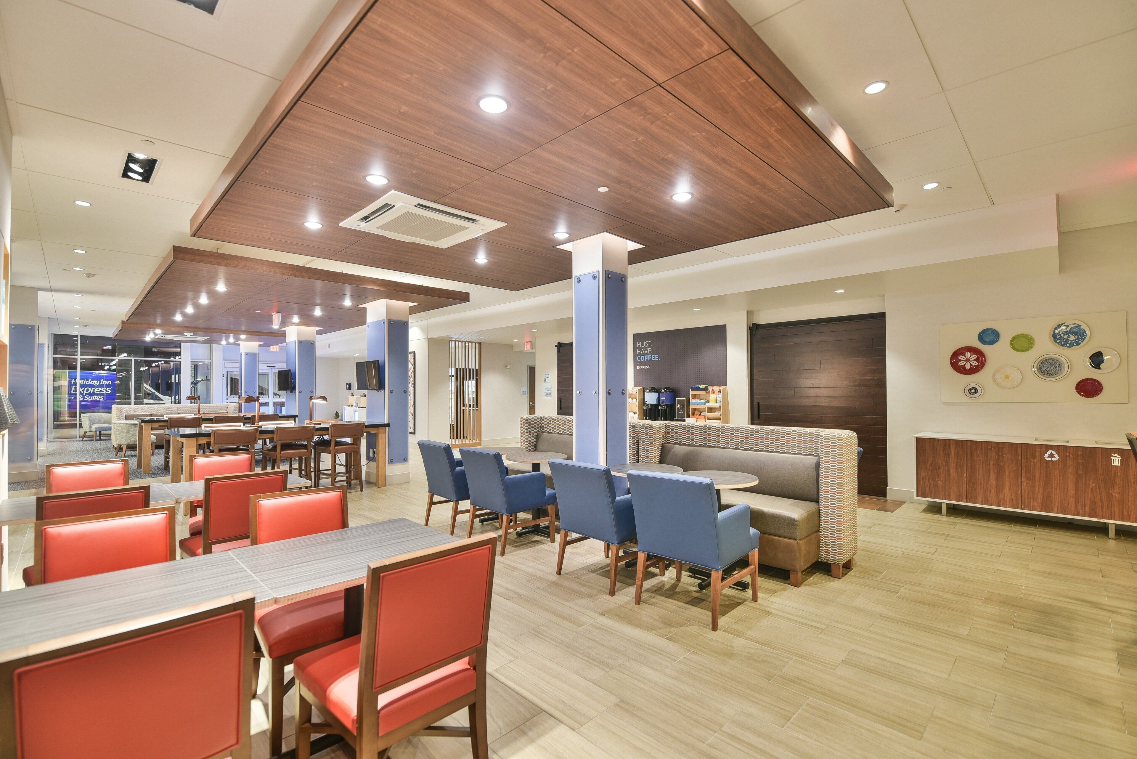 A modern hotel lobby with a dining area, seating arrangements, and a reception desk.