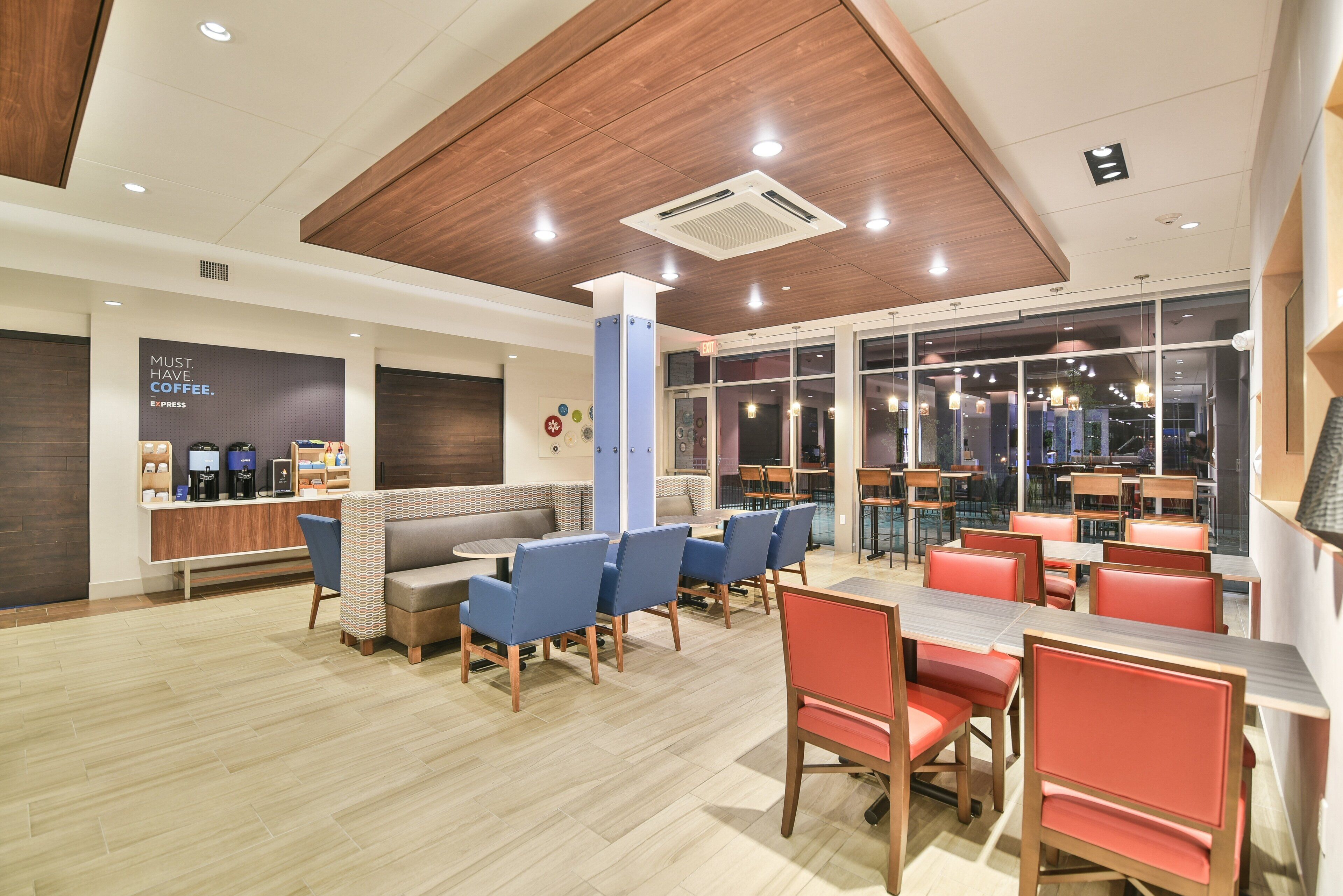 A modern cafe interior with seating arrangements, a coffee station, and a view through large windows.