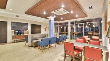 A modern cafe interior with seating arrangements, a coffee station, and a view through large windows.