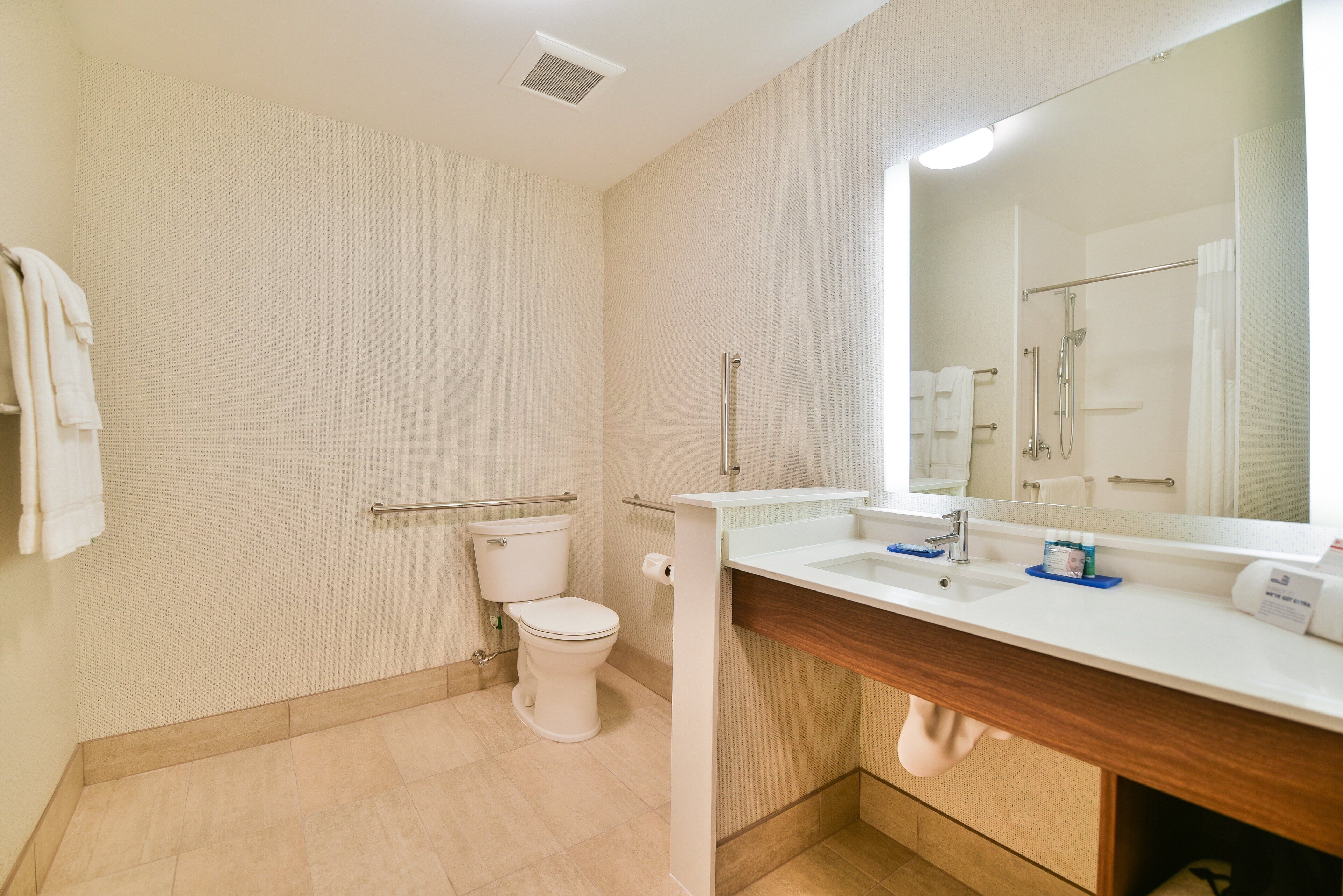 A bathroom with a toilet, sink, mirror, and shower.