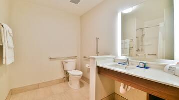 A bathroom with a toilet, sink, mirror, and shower.